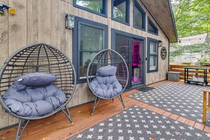 A wooden building with large windows and a door, two wicker chairs with cushions, and a patterned rug on the floor. - Poconos Cabin w/ Sauna! Lakes ~ Skiing ~ Fire Pit (Big Bass Lake)