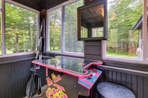 A room with a glass-top arcade table, a mirror, and a view of the outdoors. - Poconos Cabin w/ Sauna! Lakes ~ Skiing ~ Fire Pit (Big Bass Lake)