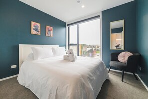 Une chambre d’hôtel moderne avec un grand lit, une chaise et une fenêtre donnant sur la ville.