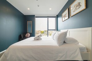 A hotel room with a large bed, a view through a window, and artwork on the wall. - 2BR with Balcony in Christchurch CBD - Sleeps 4 (Christchurch)