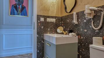 A bathroom with a marble sink, a toilet, and a shower area.