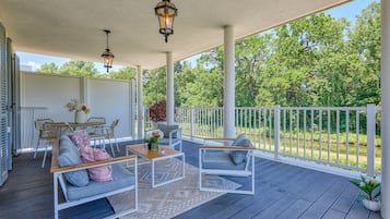 A covered outdoor deck with a seating area, a table, and hanging lanterns.