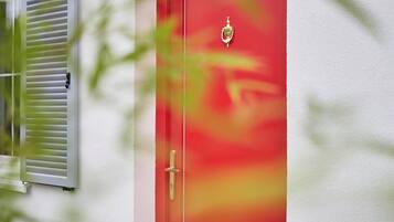 Una porta rossa con maniglia e placca di ottone.