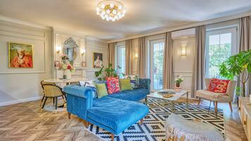 A spacious living room with a blue sofa, a coffee table, and a patterned rug.