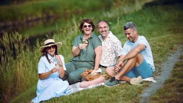 A group of people sitting on grass by a path in a natural setting.