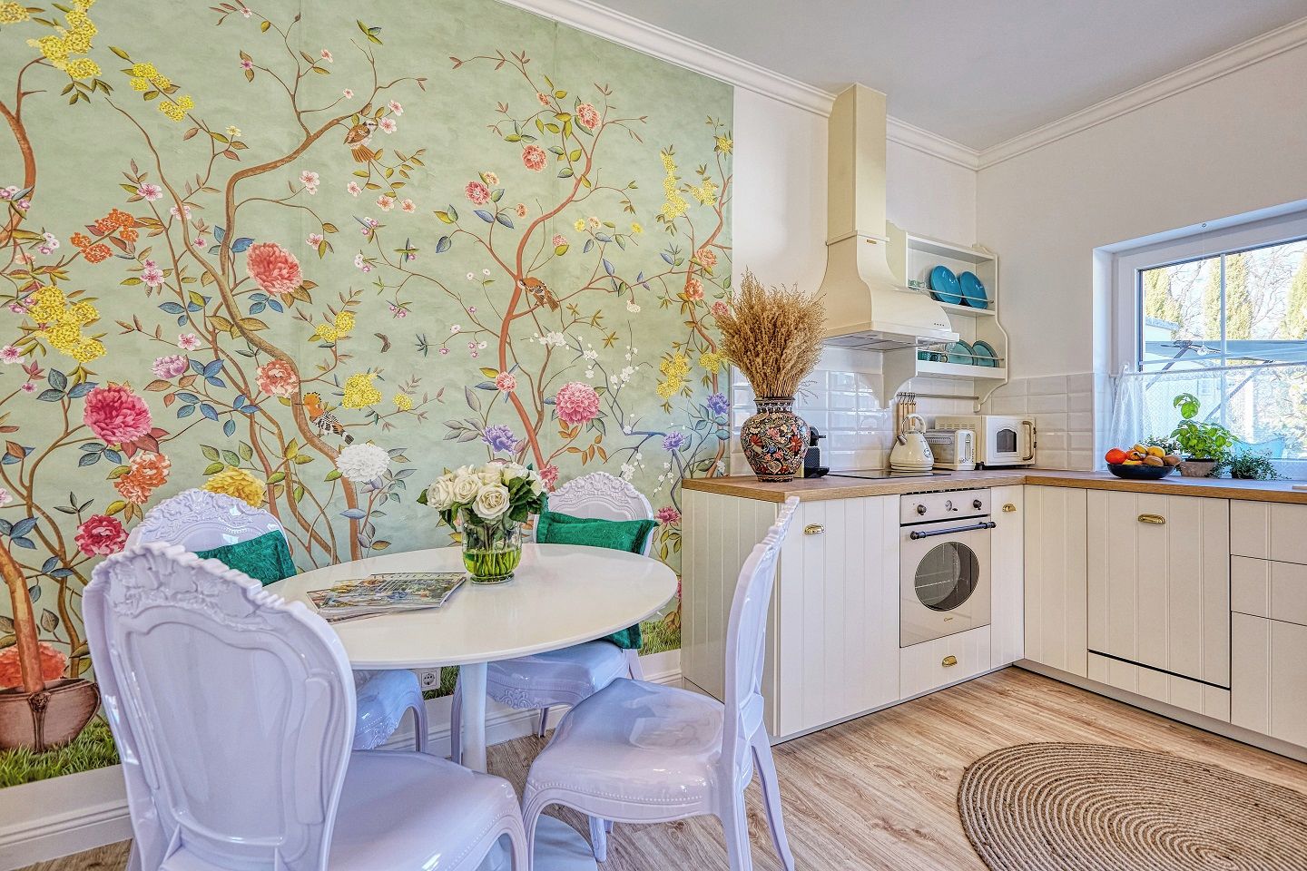 Une cuisine avec une table ronde, des chaises, une cuisinière et une fenêtre.