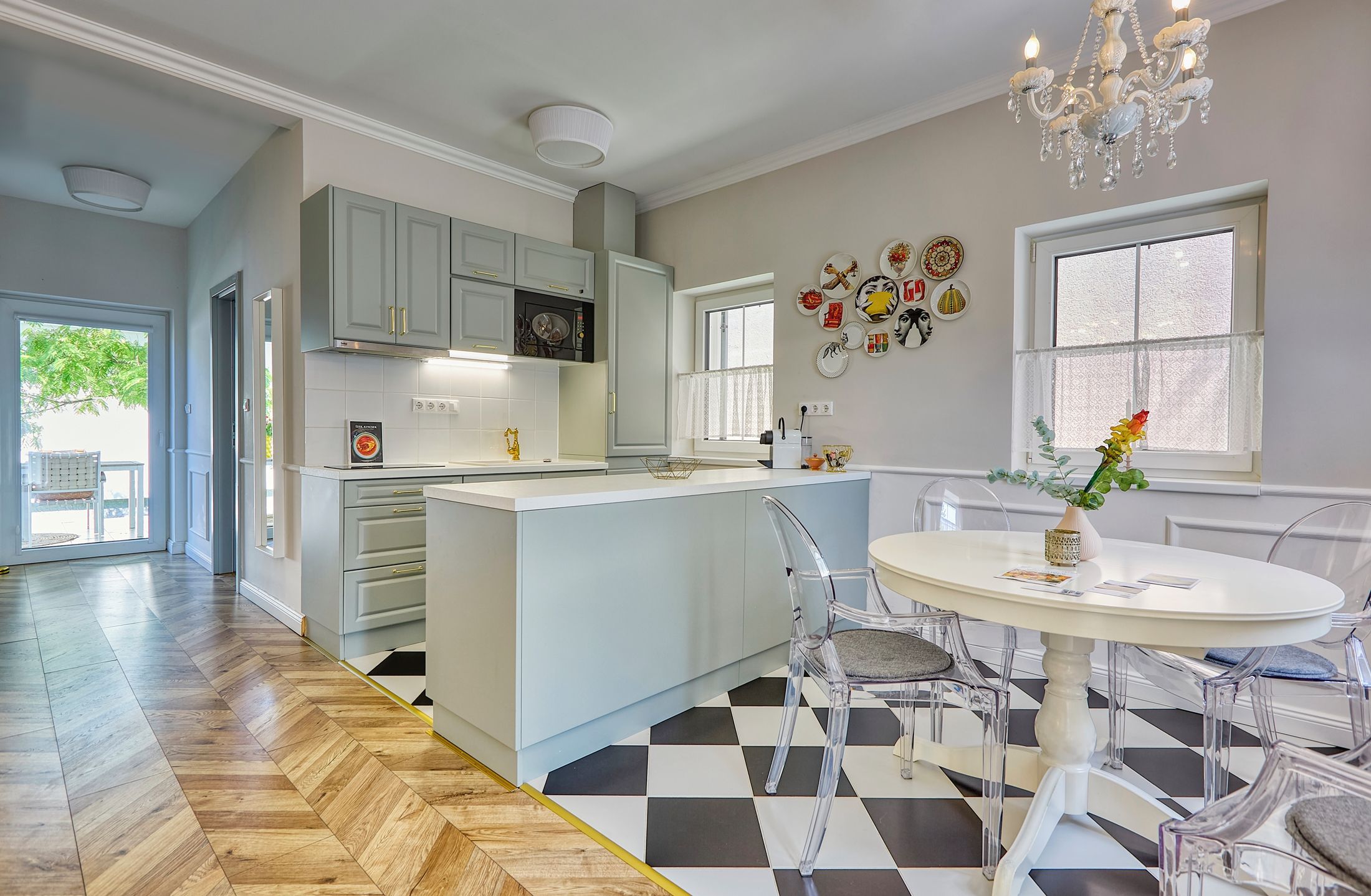 A modern kitchen with a central island, clear chairs, and a dining table.