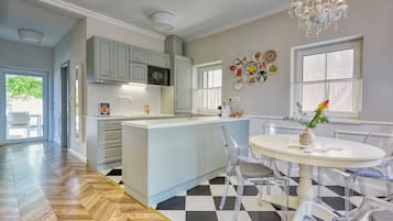 A modern kitchen with a central island, clear chairs, and a dining table.