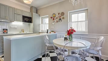 A kitchen with a central island, white cabinets, and a chandelier.