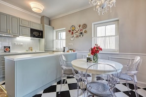 A kitchen with a central island, white cabinets, and a chandelier.