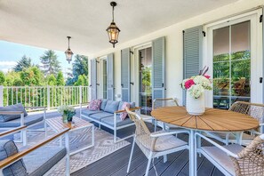 A covered outdoor patio with a sofa, chairs, a table, and hanging lanterns. - The Doors Apartments (Mosonmagyaróvár)