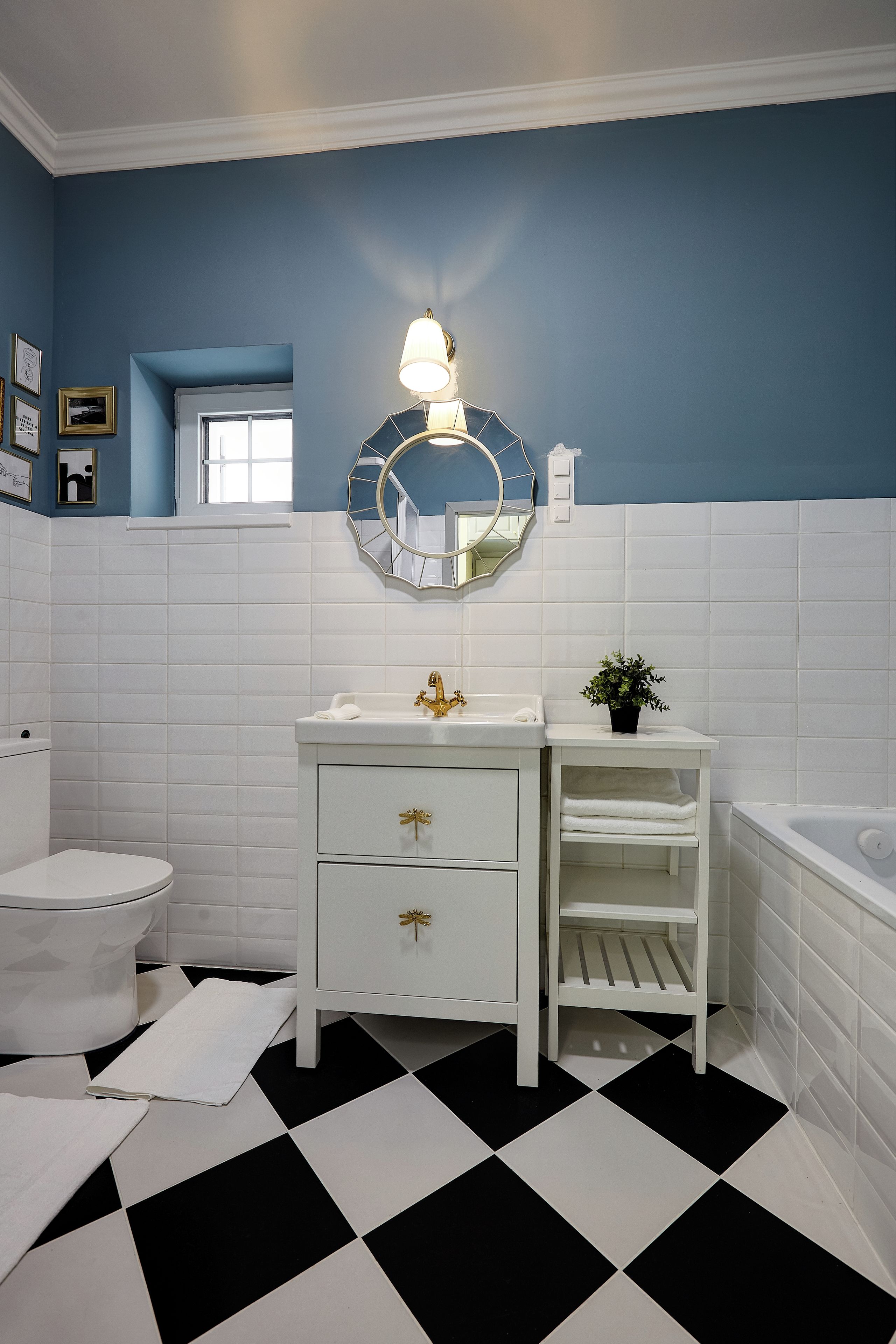 A bathroom with a white sink, a mirror, a white toilet, and a black and white checkered floor.