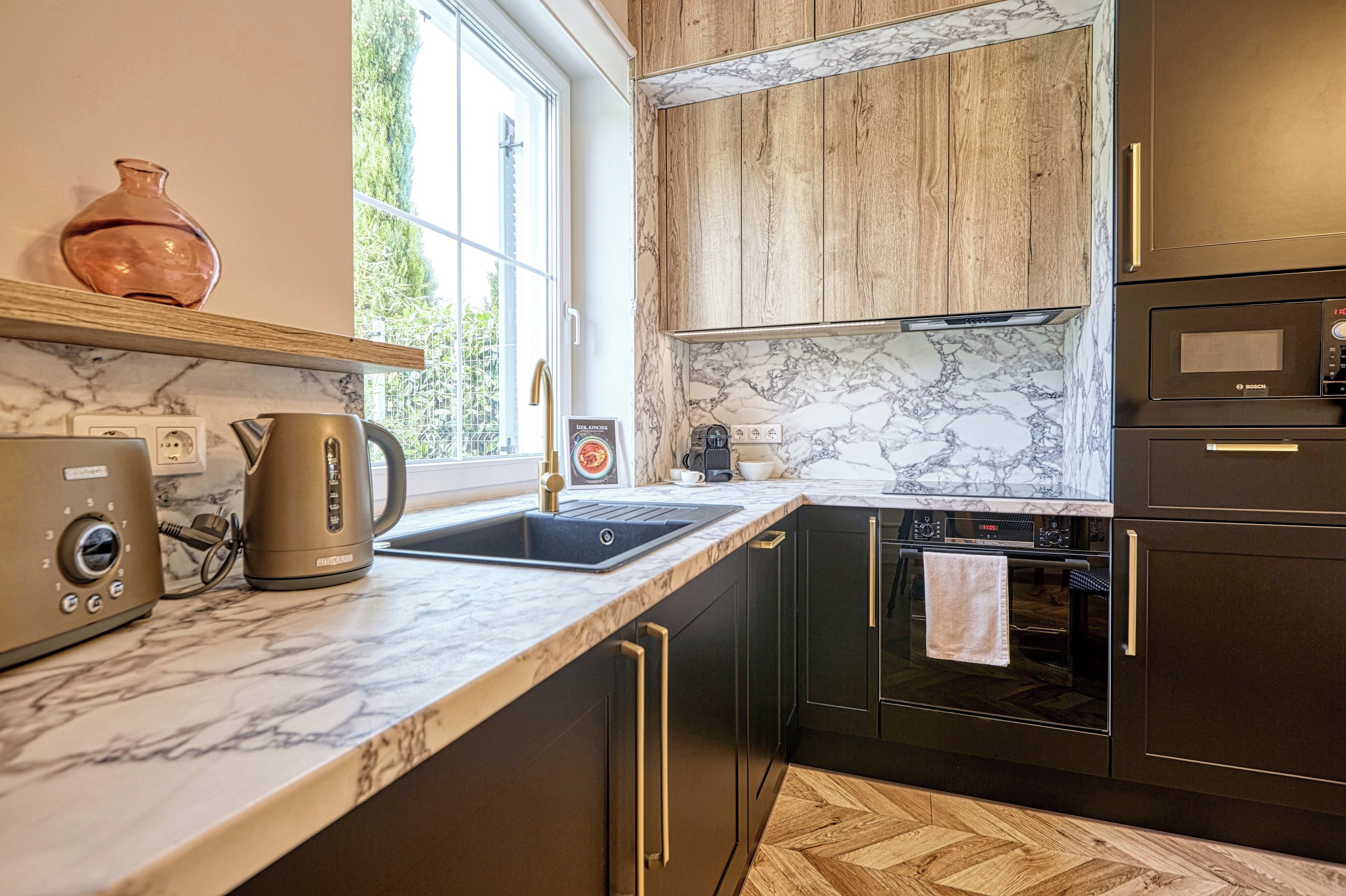 A modern kitchen with a built-in oven, a coffee machine, and a kettle on the counter.