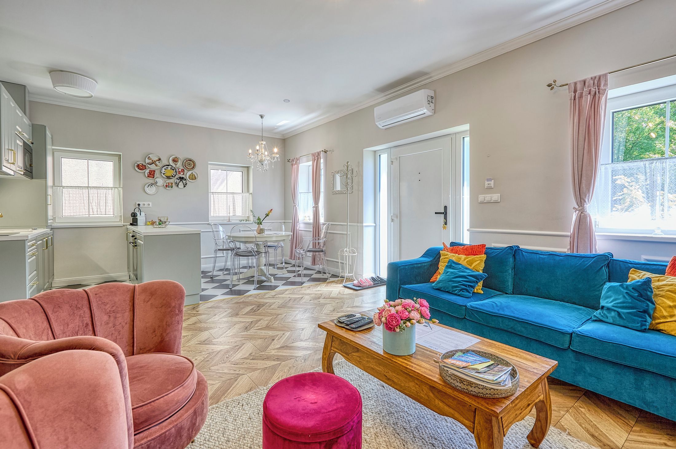 Una sala de estar con un sofá azul, un sillón rosa y una mesa de centro de madera.