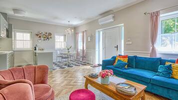 Una sala de estar con un sofá azul, un sillón rosa y una mesa de centro de madera.