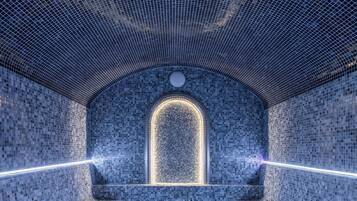 Un spa moderno con suelo y paredes alicatadas, un ventanal arqueado central y una zona de estar.