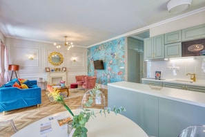 A modern living room with a blue sofa, a pink armchair, and a fireplace. - The Doors Apartments (Mosonmagyaróvár)