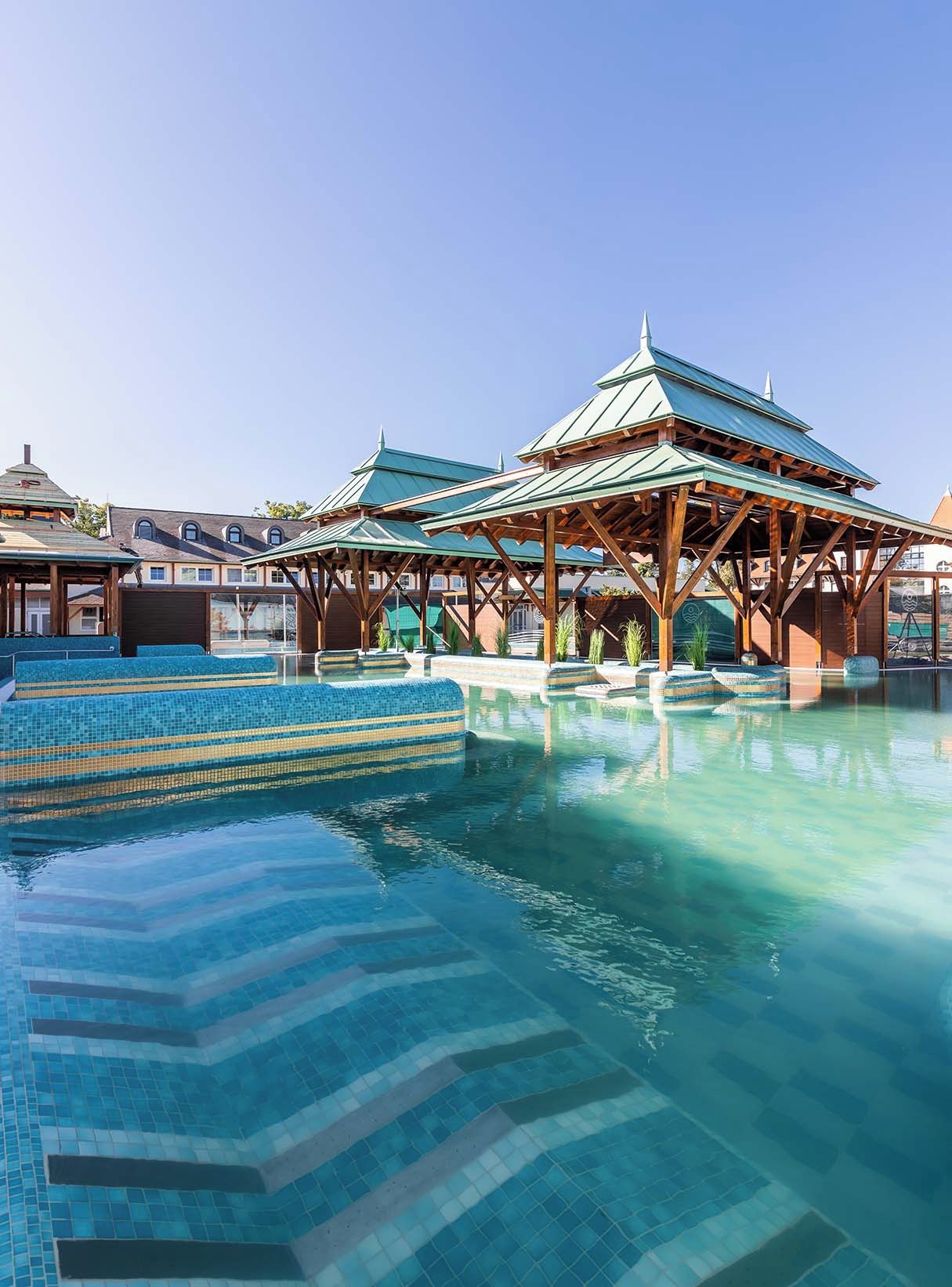 A swimming pool with tiled steps and a wooden pavilion structure.