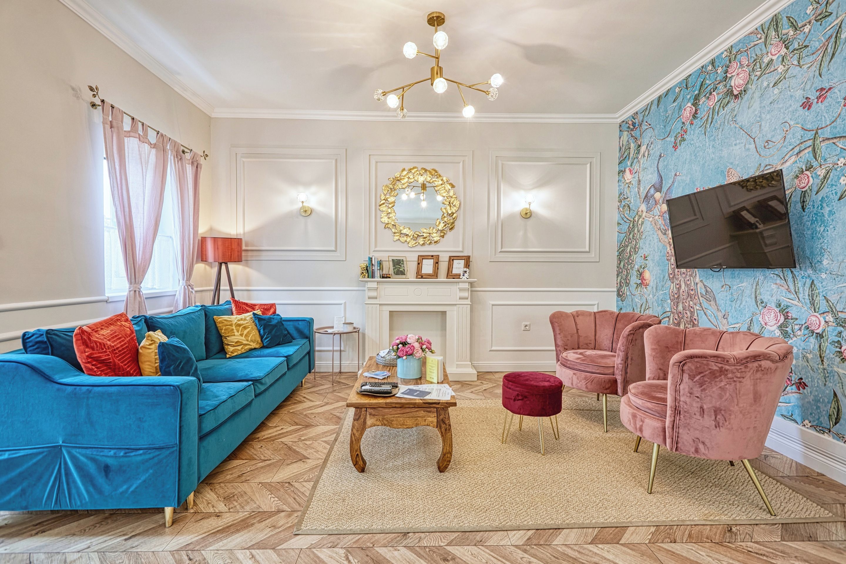 A living room with a blue sofa, a pink armchair, a wooden coffee table, and a fireplace.