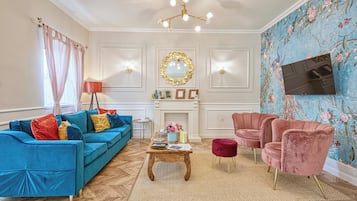 A living room with a blue sofa, a pink armchair, a wooden coffee table, and a fireplace.