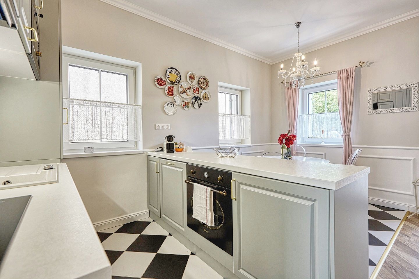 A kitchen with a central island, a built-in oven, and a chandelier.