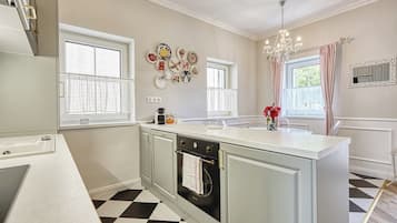 A kitchen with a central island, a built-in oven, and a chandelier.