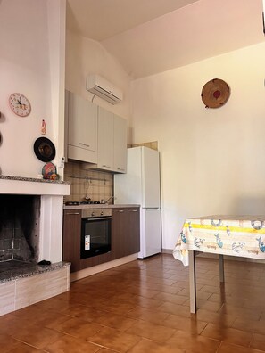 A kitchen with white cabinets, a white refrigerator, a tiled backsplash, and a table with a fish pattern tablecloth. - Cozy home just a 5-minute walk from the beach, along Geremeas Bay (Geremeas)