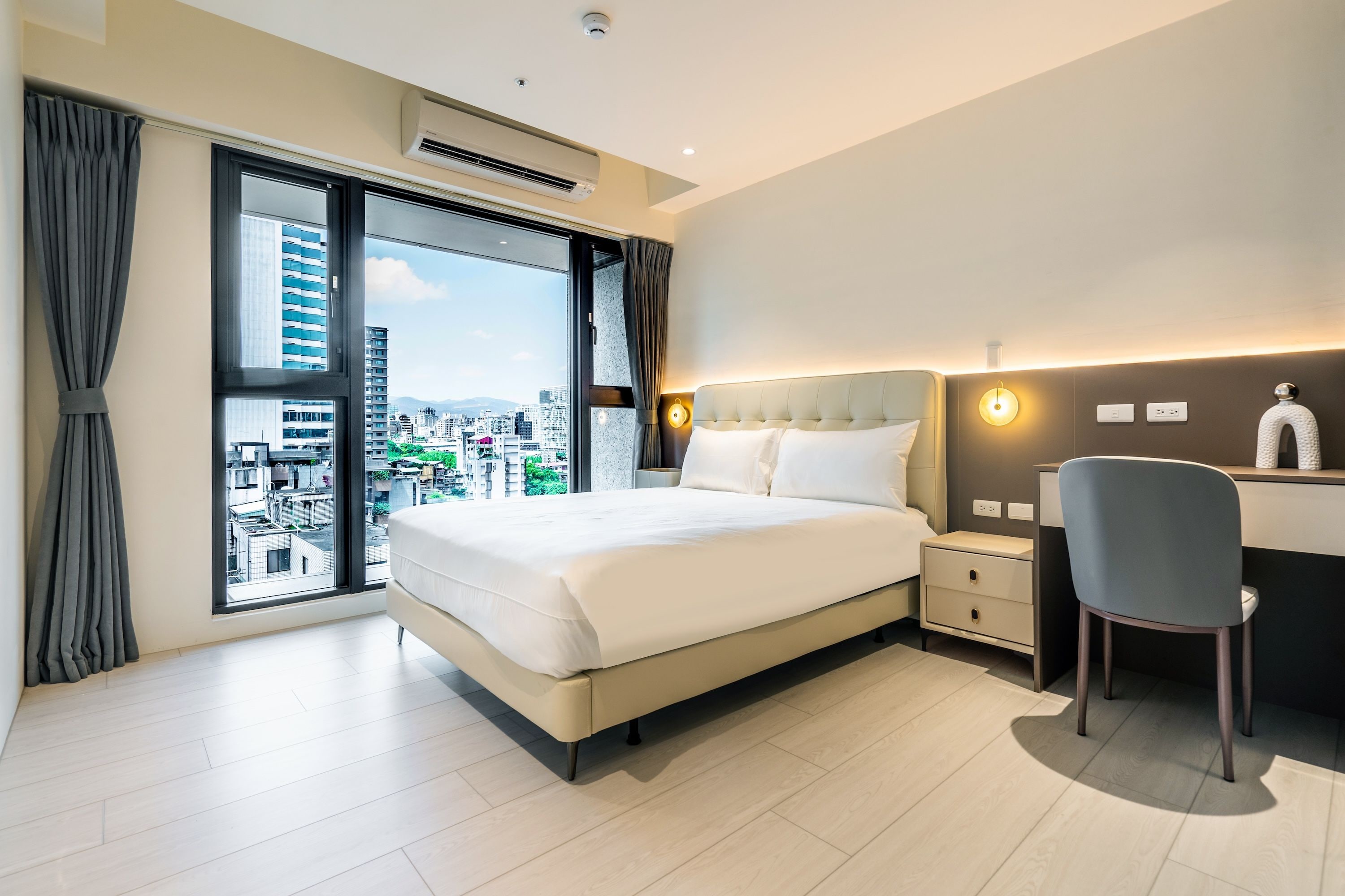 Quarto de hotel com uma cama grande, uma escrivaninha e uma cadeira.