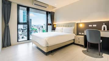Quarto de hotel com uma cama grande, uma escrivaninha e uma cadeira.
