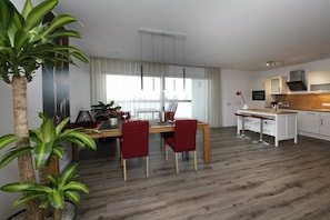 Eine moderne Küche mit weißen Schränken, einer Holzarbeitsplatte und einem Essbereich mit Tisch und Stühlen.