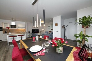 Een moderne eetruimte met een zwarte tafel, rode stoelen en een bloevas.