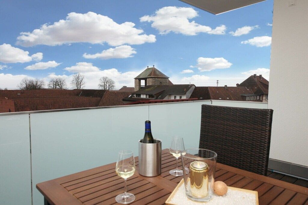Un balcon avec une table dressée pour deux personnes, une bouteille de vin et une bougie.