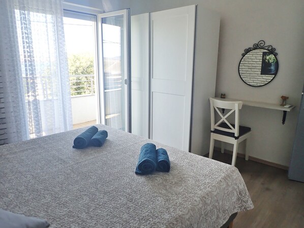 Quarto com cama, cadeira, mesinha e um objeto decorativo na parede.