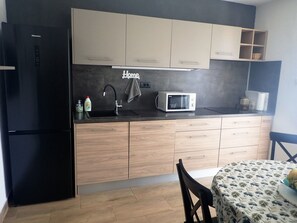 Uma cozinha compacta com geladeira preta, micro-ondas e armários de madeira.