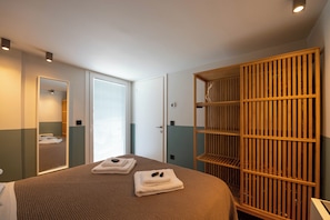 A hotel room with a bed, a wardrobe, a mirror, and a door leading to another room. - Villa Vesta Retiré (Kalamata)
