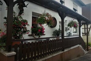 A traditional building with a white exterior, wooden porch, and a picket fence. - Holiday apartment with 2 bedrooms (Wilgartswiesen)