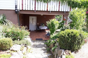 Une cour intérieure avec une table et des chaises de patio, entourée de différentes plantes et d’un petit espace aménagé en jardin.