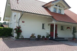 Ein weißes Gebäude mit rotem Ziegeldach und roter Tür, mit der Hausnummer 13.