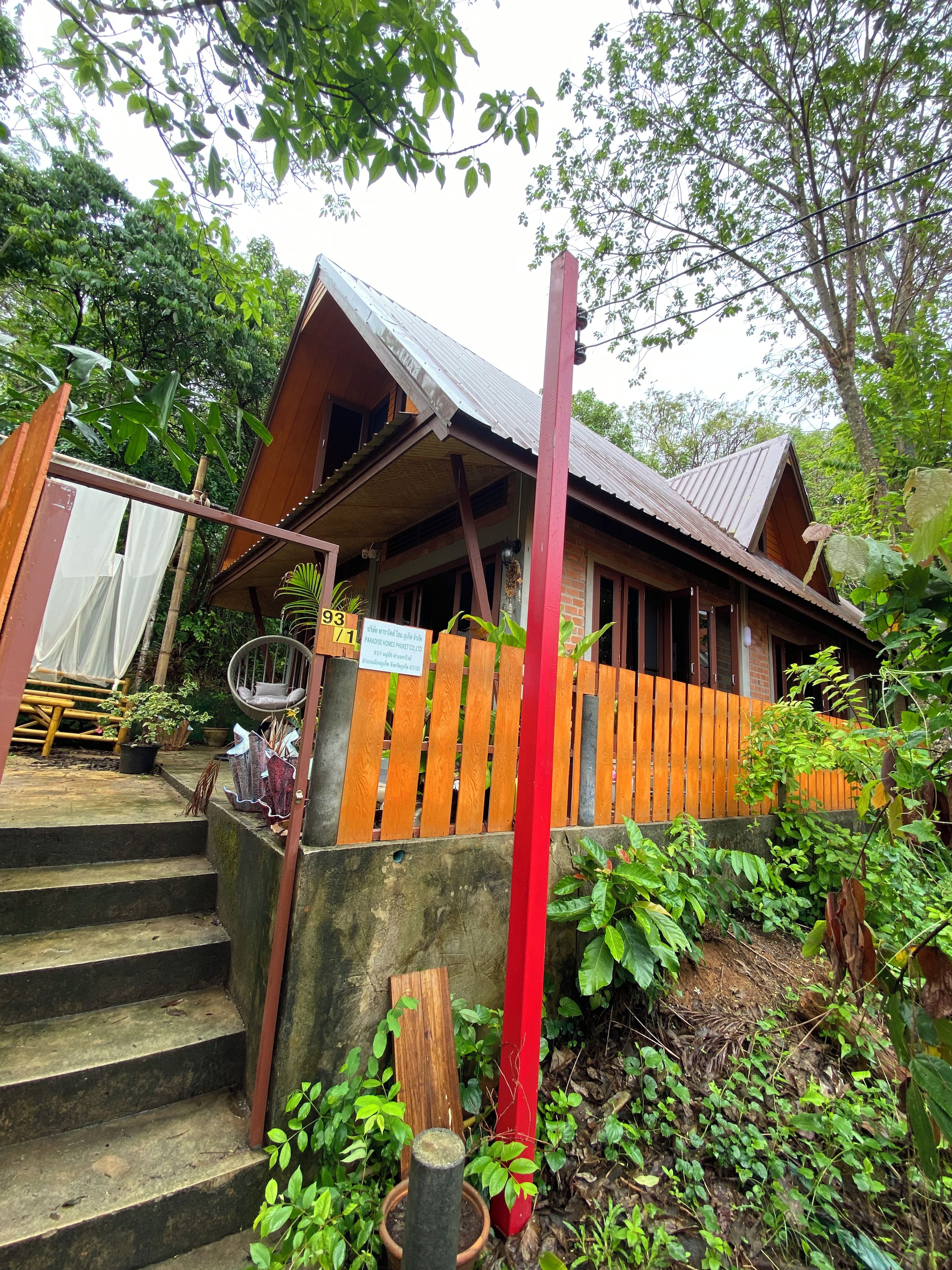 A wooden building with a porch, steps leading up to it, and a signboard.
