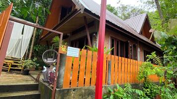 A wooden building with a porch, steps leading up to it, and a signboard.