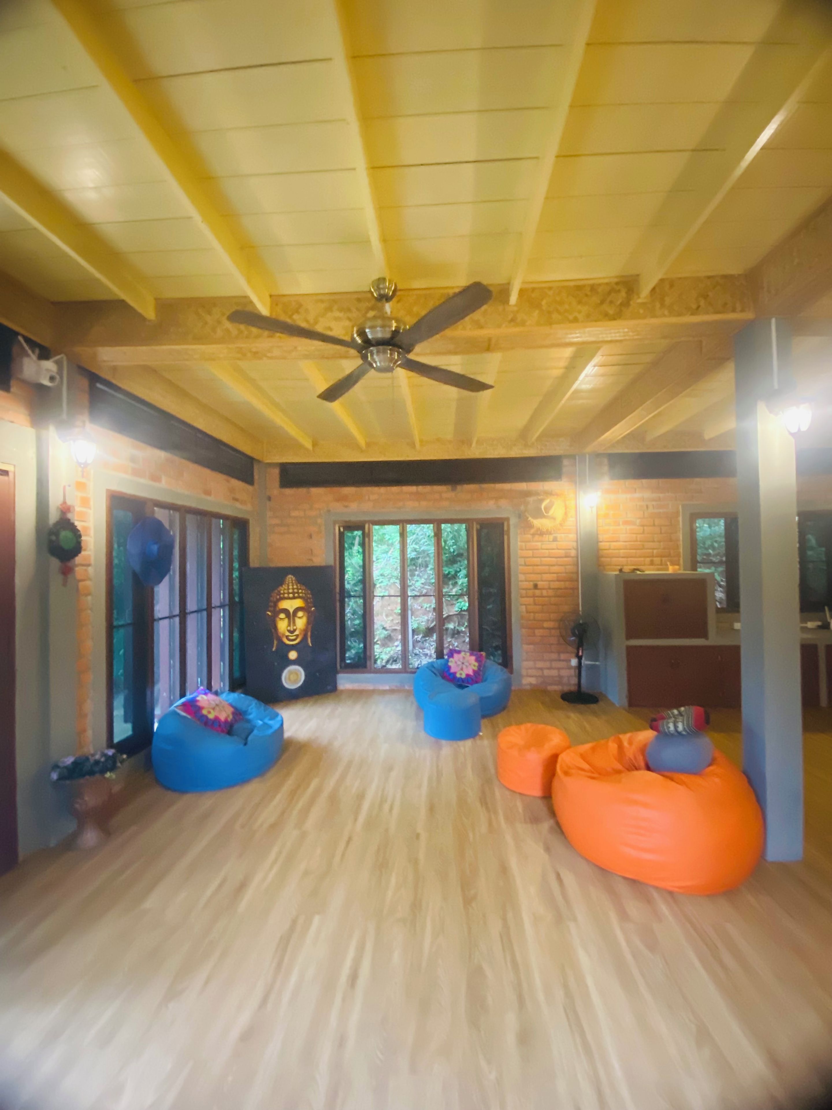 A spacious room with a high ceiling, a ceiling fan, and a large window providing a view of the outdoors.
