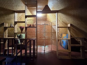 A room with a sloped ceiling, wooden shelving units, and a painting.