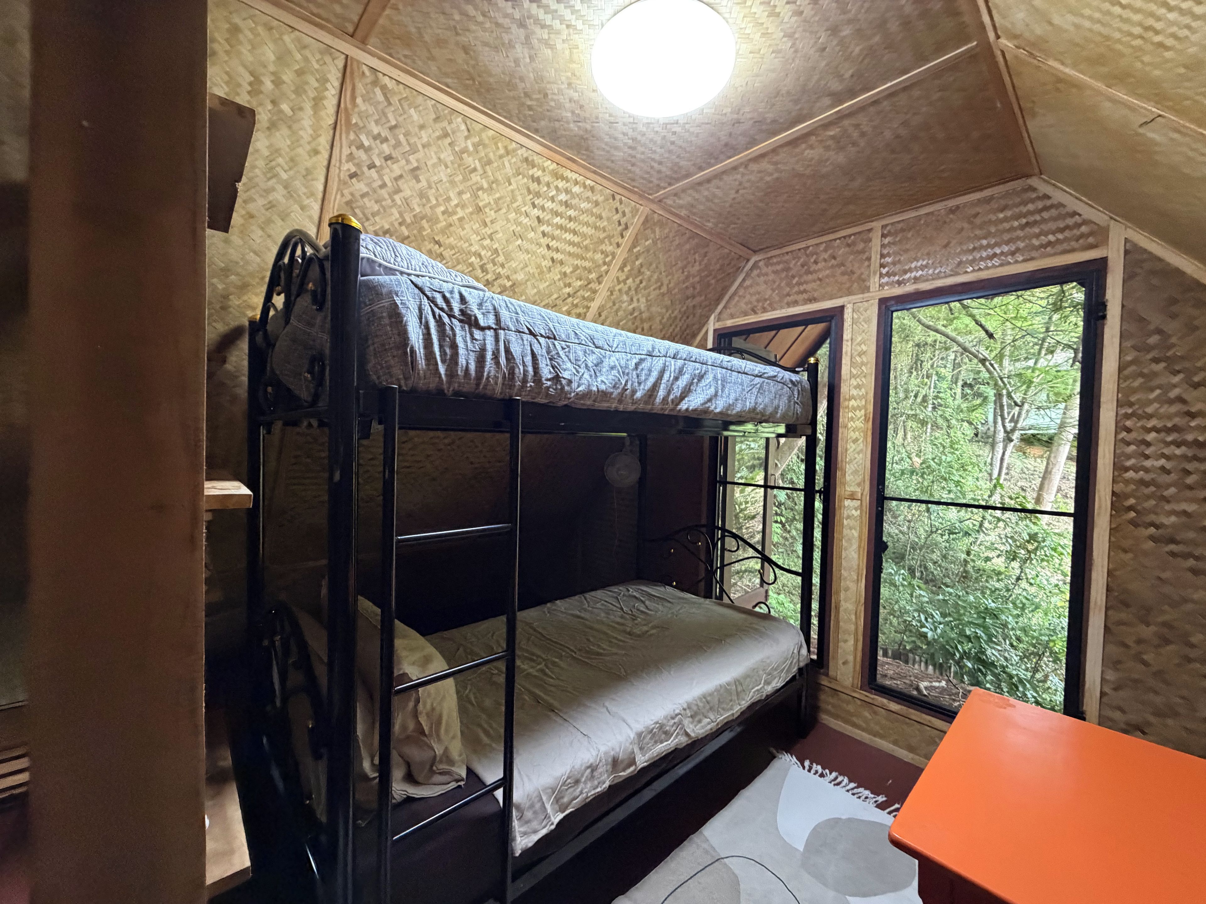Ein Stockbett in einem Zimmer mit Fenster und Blick auf Grünfläche.