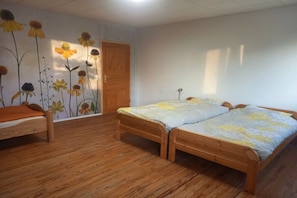 Una habitación con dos camas de madera, una silla de madera y una pared con un mural floral.