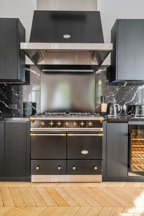 A modern kitchen with a built-in stove, black cabinets, and a marble countertop. - 200 m² Luxury on the Seine: Alma, George V, Montaigne (Paris)