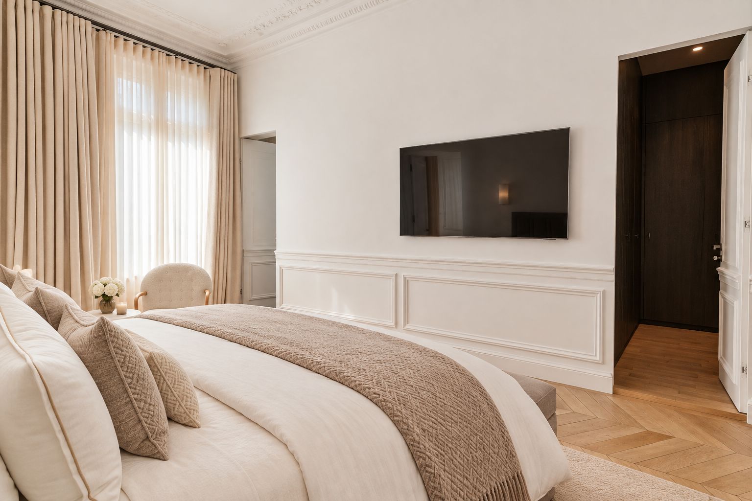 Un dormitorio con una cama grande, un televisor en la pared y una puerta que da a otra habitación.