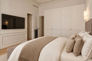 A bedroom with a large bed, a television mounted on the wall, and a wardrobe. - 200 m² Luxury on the Seine: Alma, George V, Montaigne (Paris)