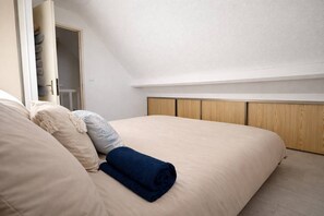 A bedroom with a bed, a wooden headboard, and a closet with a hanging bag. - Fleur des Dunes - Beach - Pool - Garden (Erdeven)