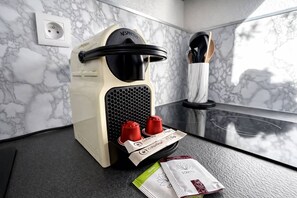 Een koffieapparaat met twee rode bekers en twee koffiekapsules op een marmeren aanrecht.