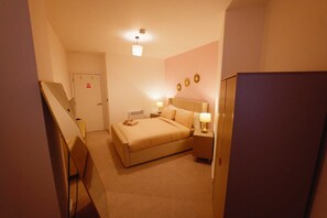 Ein Hotelzimmer mit einem Bett, Nachttischen, einem Schreibtisch und einem Kleiderschrank.